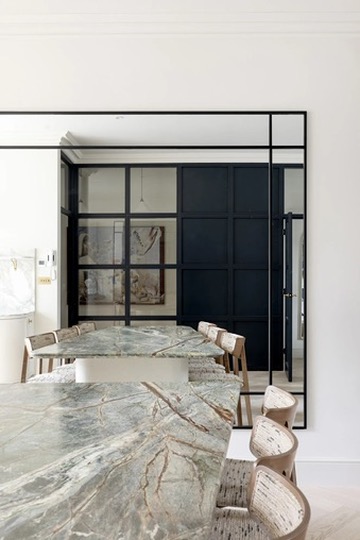Green marble dining table beside black panelled Crittall wall