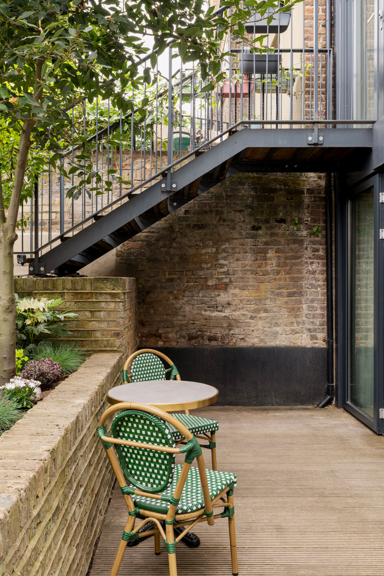 Lower patio with bistro table beneath the steel staircase