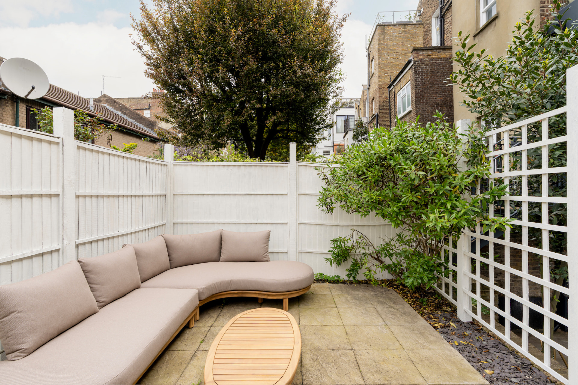 Upper garden terrace with curved outdoor sofa and planting