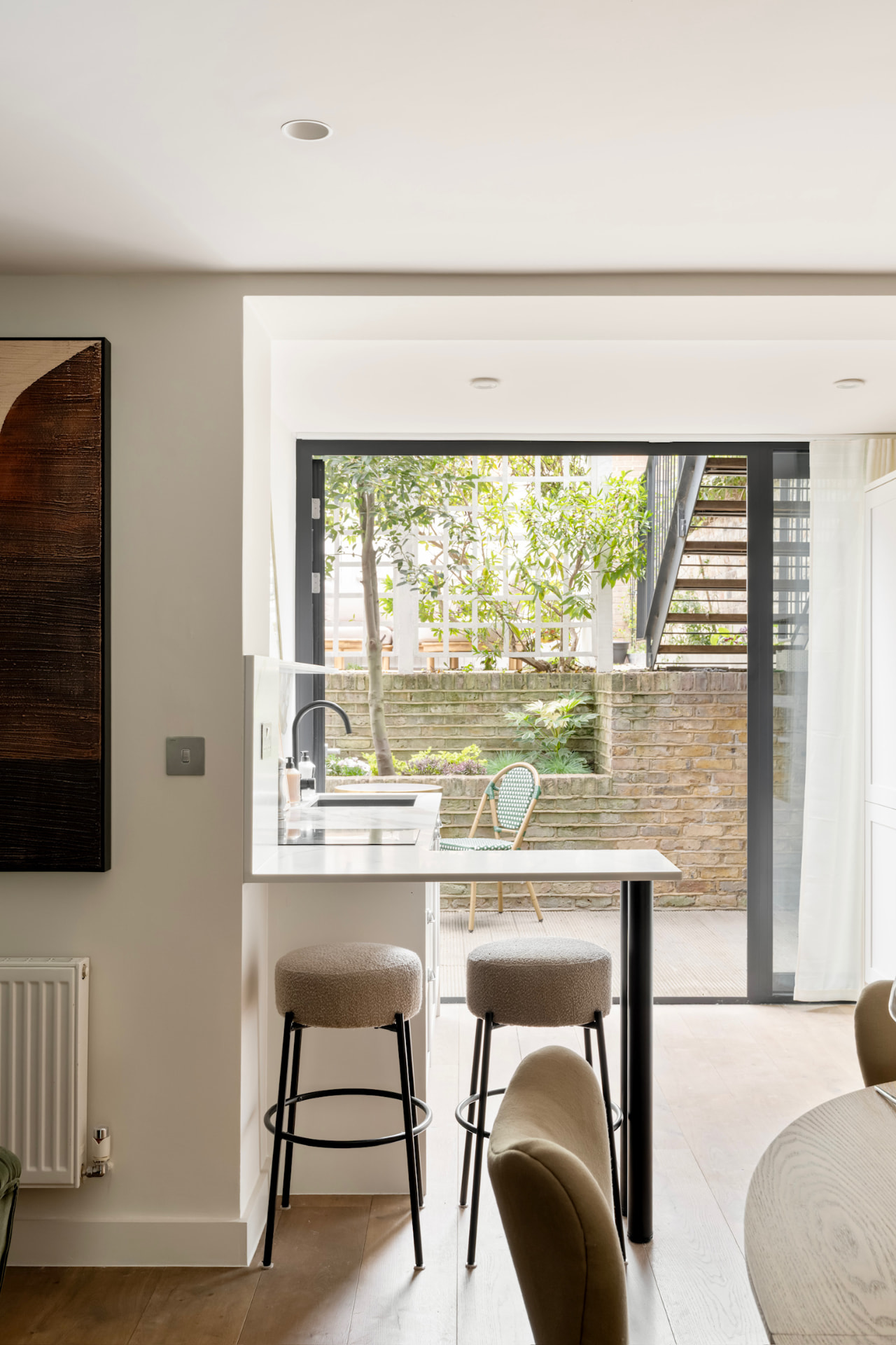 Breakfast bar with boucle stools and open doors to the garden