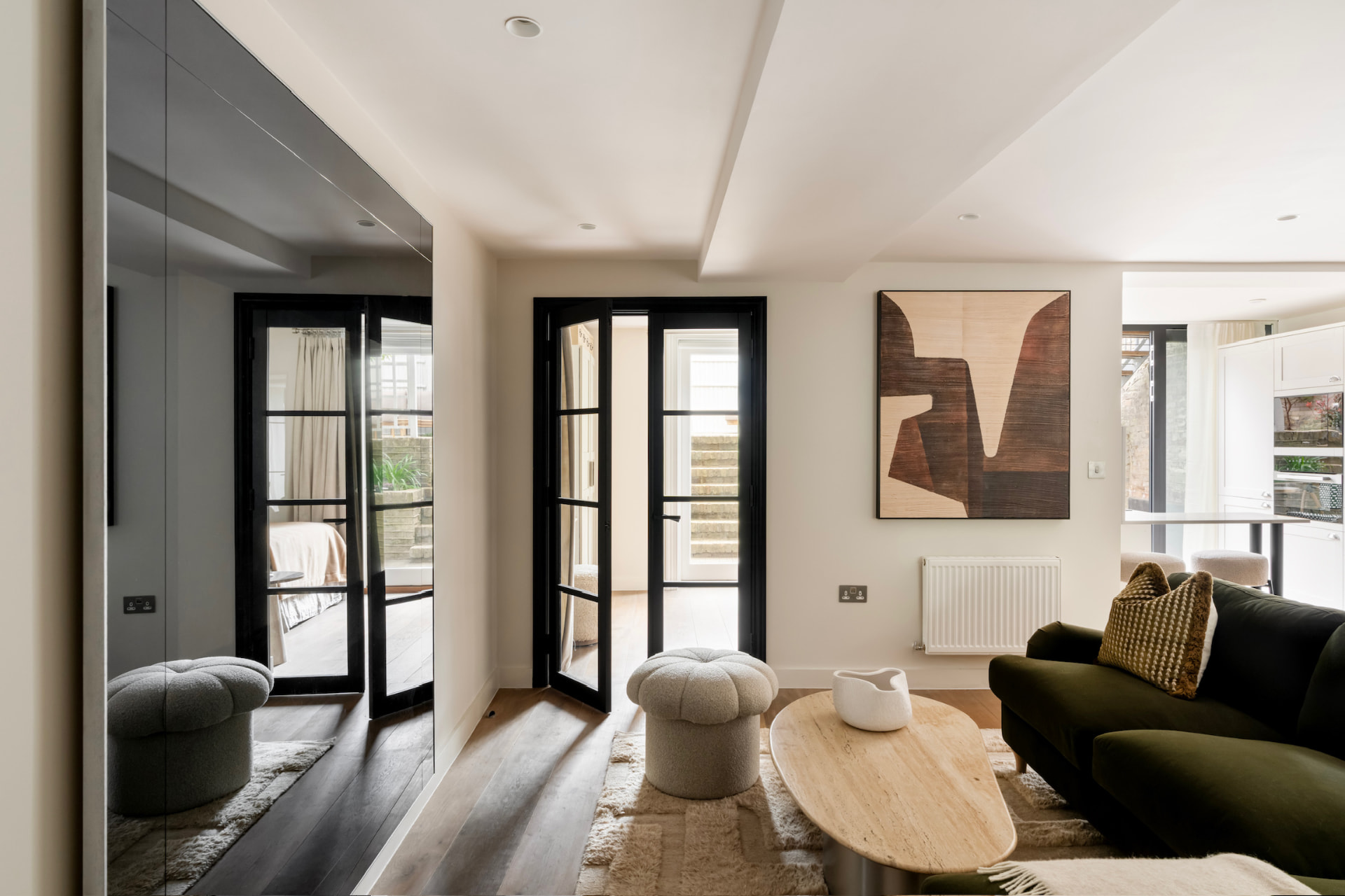 Sitting room with full-height mirrored wall and black Crittall doors