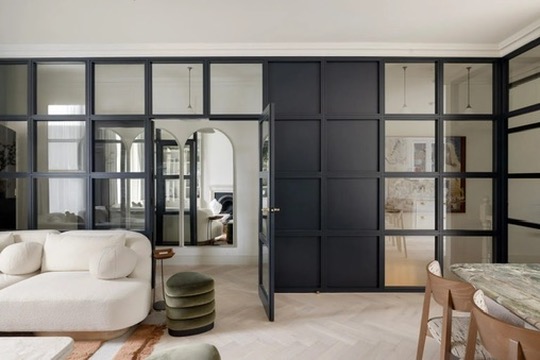 Living room with curved sofa and black Crittall glazed partition doors