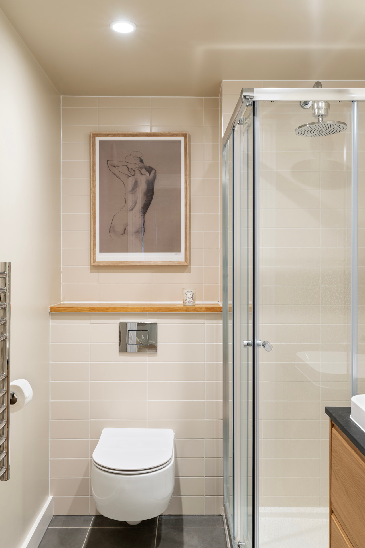 Shower room with tiled walls, oak shelf and framed artwork