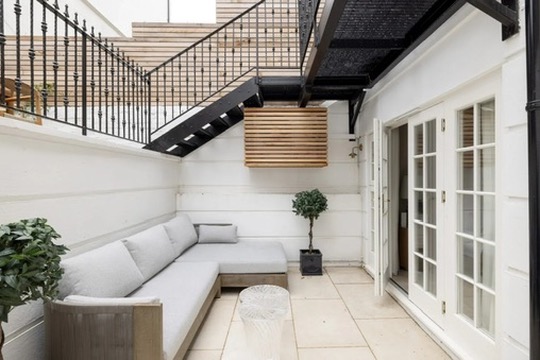 Lower patio with built-in seating and potted olive tree